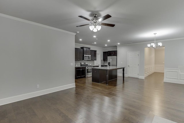 kitchen featuring dark wood-style floors, a breakfast bar area, appliances with stainless steel finishes, a kitchen island with sink, and ceiling fan with notable chandelier