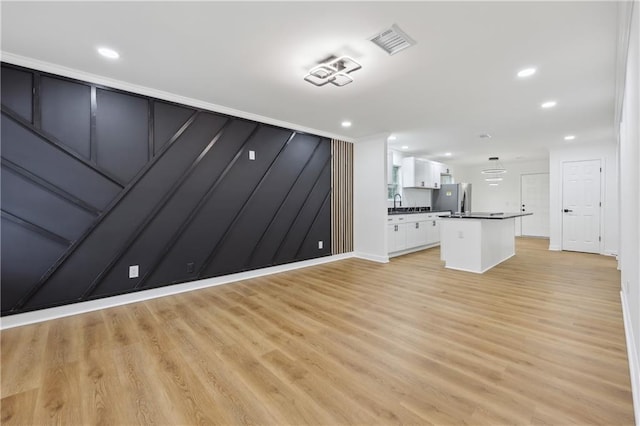 unfurnished living room with sink and light hardwood / wood-style floors