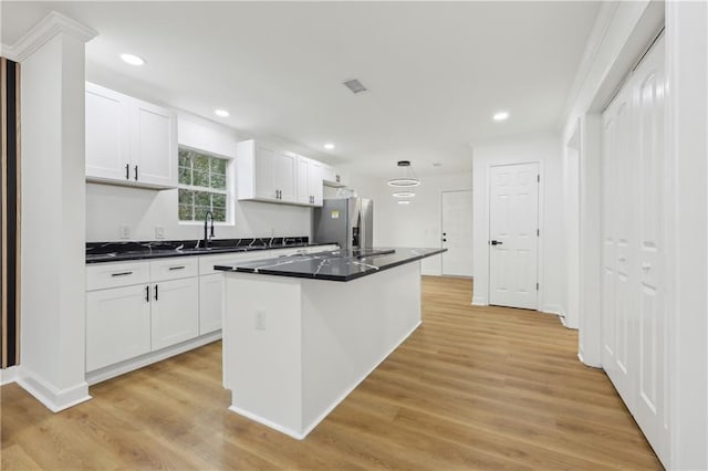 kitchen with stainless steel refrigerator with ice dispenser, sink, a kitchen island with sink, light hardwood / wood-style floors, and white cabinets