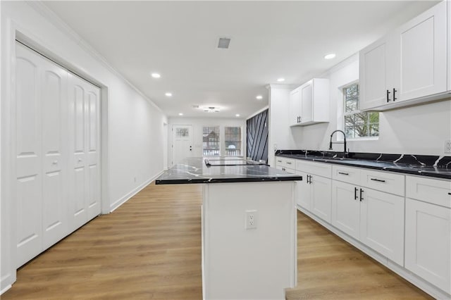 kitchen featuring white cabinetry, a kitchen island, sink, and light hardwood / wood-style flooring