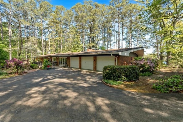 view of front of home featuring an attached garage, asphalt driveway, and brick siding
