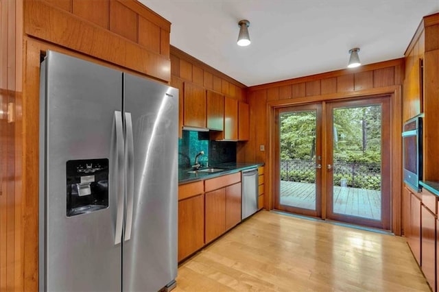 kitchen featuring appliances with stainless steel finishes, dark countertops, french doors, light wood-type flooring, and wooden walls