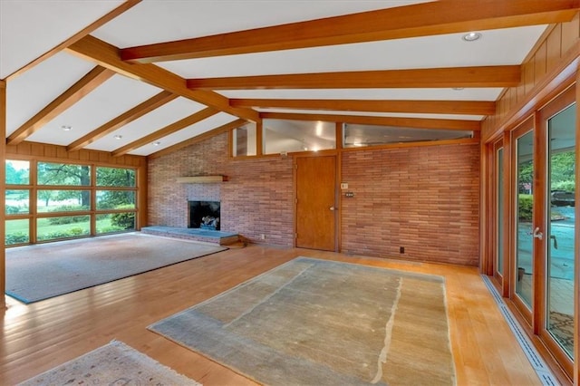 unfurnished living room featuring brick wall, a fireplace, and wood finished floors