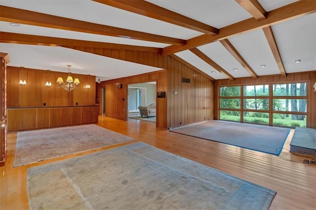 unfurnished living room with a chandelier, wood finished floors, and wood walls
