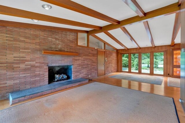 unfurnished living room with beam ceiling, a fireplace, wood finished floors, and high vaulted ceiling