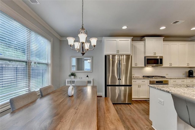 4335 Bellview Ln, Duluth, GA 30097 - kitchen with appliances with stainless steel finishes, a chandelier, plenty of natural light, crown molding, and white cabinets