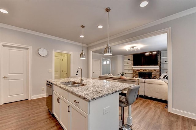 4335 Bellview Ln, Duluth, GA 30097 - kitchen with stainless steel dishwasher, a stone fireplace, white cabinets, a kitchen bar, and light wood-style floors