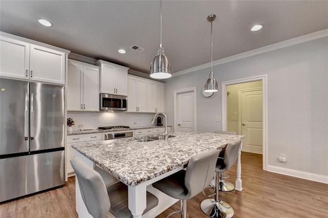 4335 Bellview Ln, Duluth, GA 30097 - kitchen with stainless steel appliances, a breakfast bar, white cabinetry, ornamental molding, and light wood-style floors