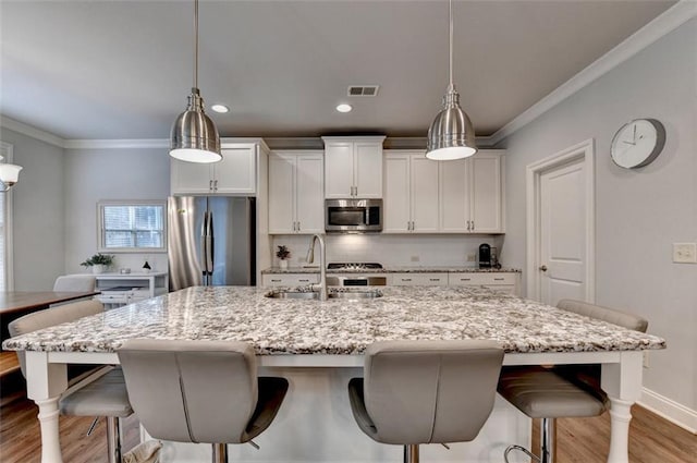 4335 Bellview Ln, Duluth, GA 30097 - kitchen with stainless steel appliances, a breakfast bar area, light wood-style flooring, backsplash, and ornamental molding