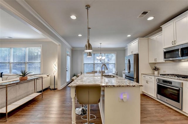 4335 Bellview Ln, Duluth, GA 30097 - kitchen featuring appliances with stainless steel finishes, wood finished floors, crown molding, light stone countertops, and a breakfast bar area