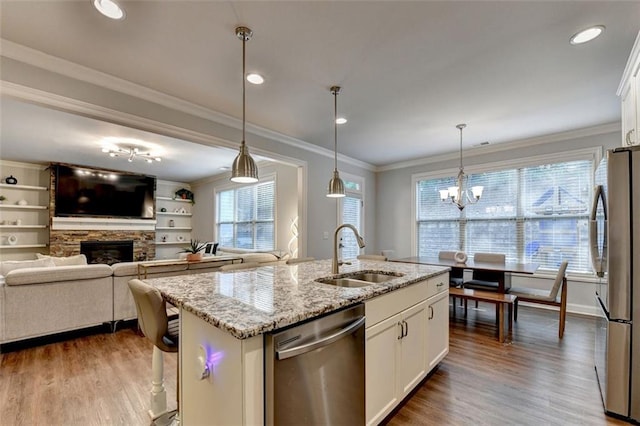 4335 Bellview Ln, Duluth, GA 30097 - kitchen featuring stainless steel appliances, wood finished floors, a stone fireplace, white cabinetry, and ornamental molding