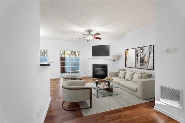 living area with ceiling fan, visible vents, wood finished floors, and a glass covered fireplace