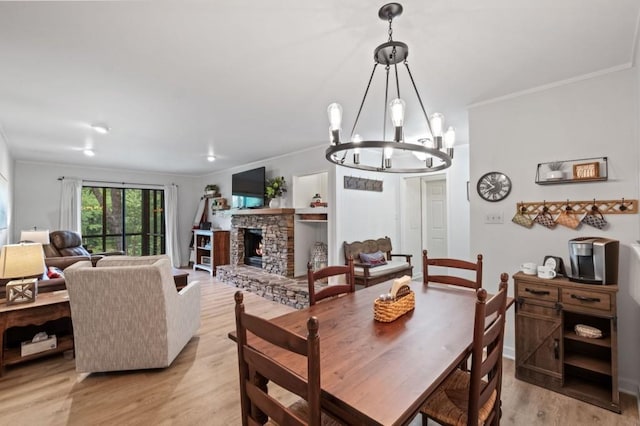 dining room with a chandelier, ornamental molding, a fireplace, and light wood-style flooring