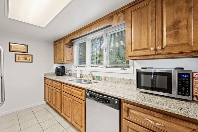 kitchen with light tile patterned floors, light stone counters, freestanding refrigerator, electric range oven, and brown cabinetry