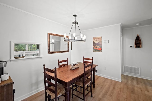 dining space with baseboards, visible vents, crown molding, light wood-type flooring, and a chandelier