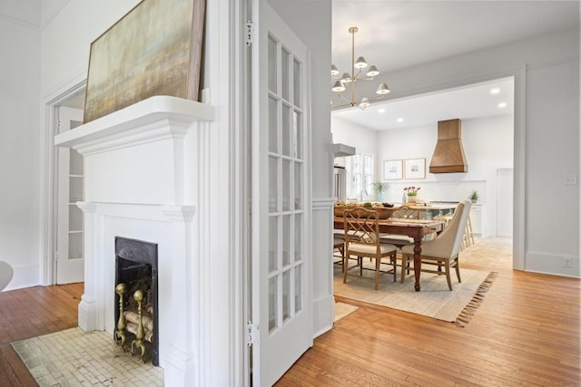 living area with light wood-style floors, a chandelier, a fireplace with flush hearth, and recessed lighting