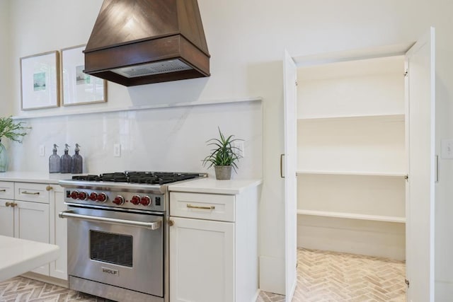 kitchen featuring designer range, custom exhaust hood, tasteful backsplash, and white cabinets