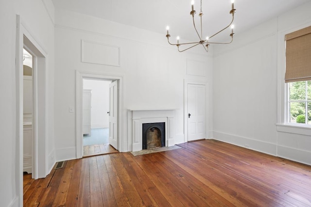 unfurnished living room with a chandelier, hardwood / wood-style floors, and baseboards