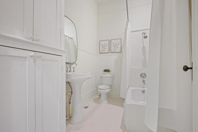 bathroom featuring toilet, tile patterned floors, shower / bath combo with shower curtain, and a sink