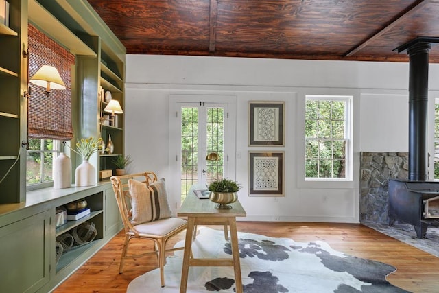 sunroom featuring a wood stove, healthy amount of natural light, and beamed ceiling