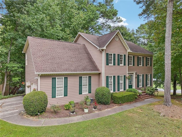 colonial inspired home featuring a garage and a front lawn