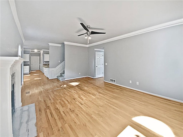 unfurnished living room with crown molding, ceiling fan, and light hardwood / wood-style flooring