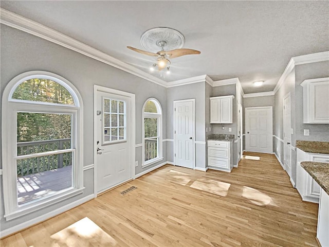 interior space with ceiling fan, light hardwood / wood-style floors, crown molding, and white cabinetry