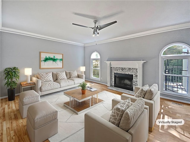 living room featuring crown molding, ceiling fan, a fireplace, and light hardwood / wood-style flooring