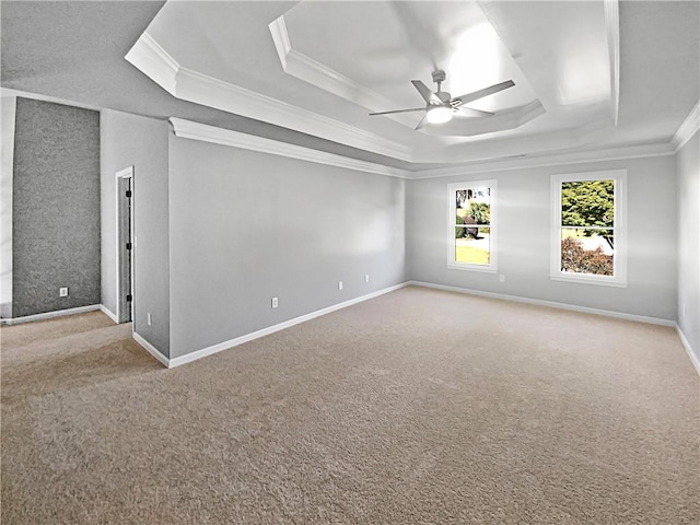 empty room with ornamental molding, ceiling fan, a tray ceiling, and light carpet