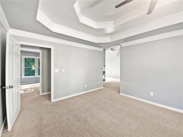 carpeted spare room with ceiling fan, crown molding, and a tray ceiling