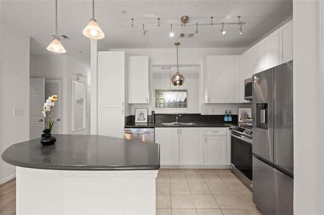 kitchen with dark countertops, appliances with stainless steel finishes, white cabinets, and a sink