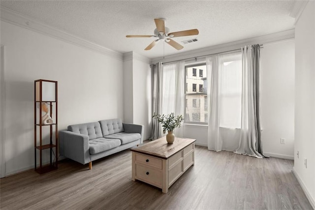 living room with visible vents, crown molding, a textured ceiling, and wood finished floors