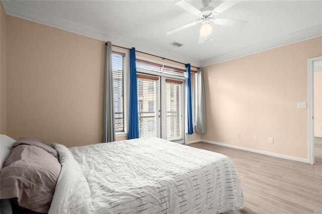 bedroom featuring baseboards, visible vents, a ceiling fan, wood finished floors, and crown molding