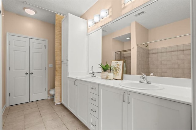 bathroom featuring a shower, double vanity, toilet, a sink, and tile patterned floors