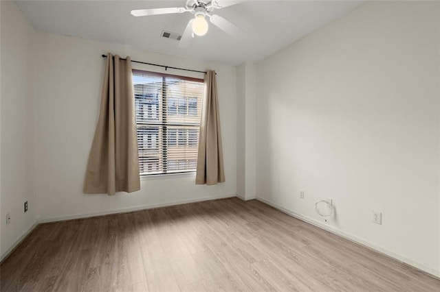 unfurnished room featuring light wood finished floors, baseboards, visible vents, and a ceiling fan