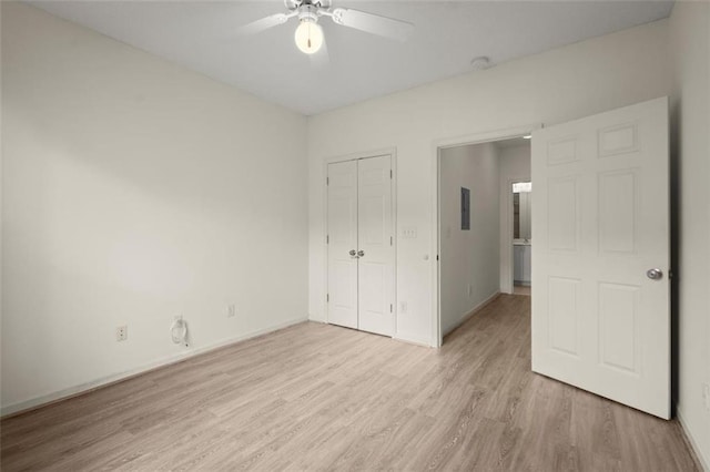 unfurnished bedroom featuring light wood-type flooring, a ceiling fan, baseboards, and a closet