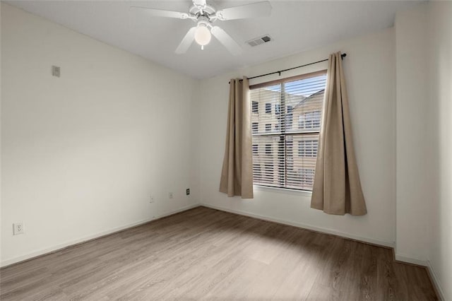 empty room featuring baseboards, wood finished floors, visible vents, and a ceiling fan