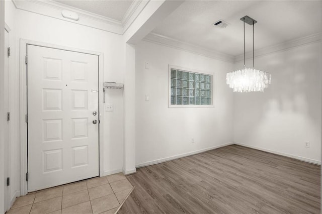 entrance foyer with a notable chandelier, visible vents, baseboards, light wood-style floors, and crown molding