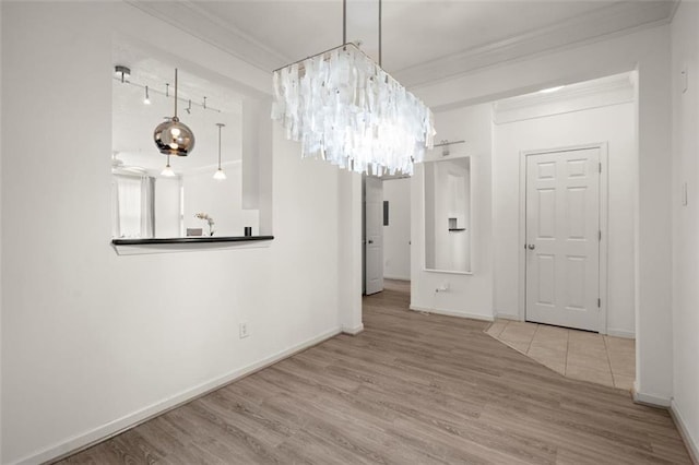 unfurnished dining area featuring baseboards, an inviting chandelier, wood finished floors, and crown molding