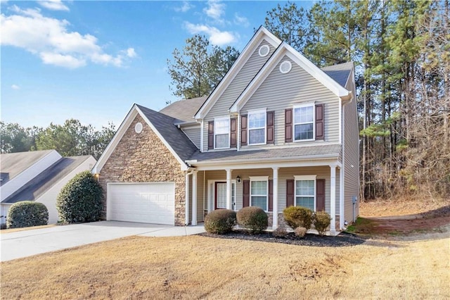 traditional home with a porch, a garage, stone siding, driveway, and a front lawn