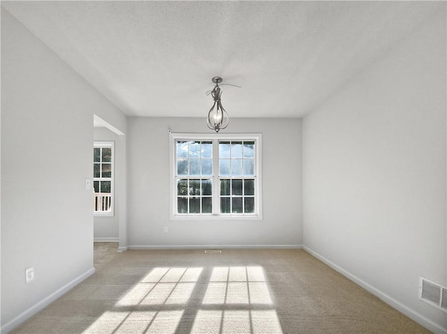 unfurnished room featuring a textured ceiling and light colored carpet