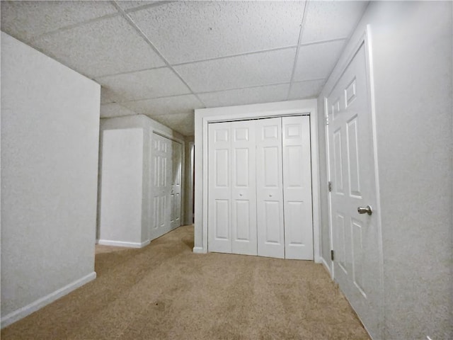 unfurnished bedroom featuring a paneled ceiling and light colored carpet