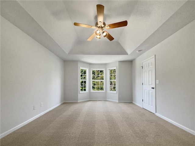 carpeted empty room featuring lofted ceiling, a tray ceiling, and ceiling fan