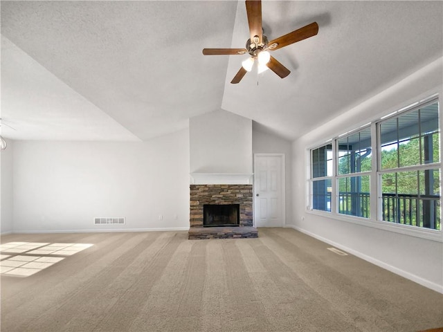 unfurnished living room featuring a textured ceiling, vaulted ceiling, light carpet, a stone fireplace, and ceiling fan