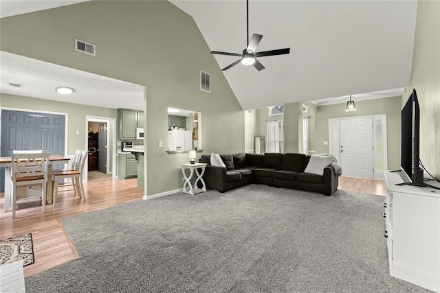 3625 Wapakonata Trl, Bethlehem, GA 30620 - living room featuring a ceiling fan, high vaulted ceiling, light wood-style flooring, baseboards, and light carpet