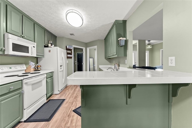3625 Wapakonata Trl, Bethlehem, GA 30620 - kitchen featuring green cabinets, white appliances, a breakfast bar area, light wood finished floors, and a textured ceiling