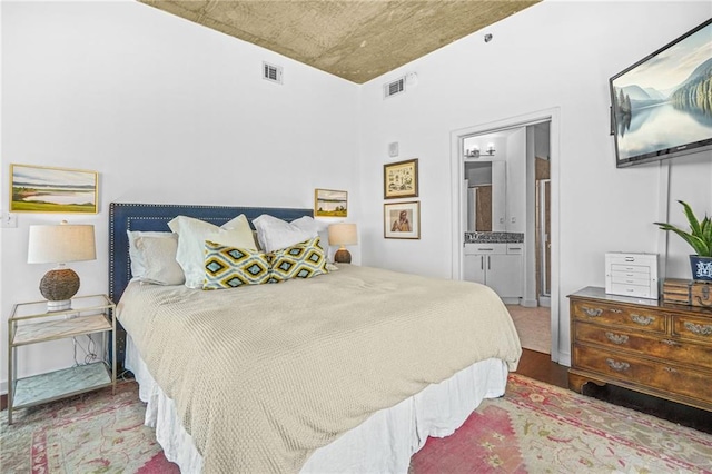 bedroom featuring visible vents, connected bathroom, and wood finished floors