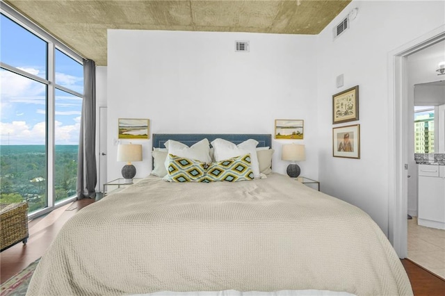 bedroom featuring a wall of windows, visible vents, and multiple windows