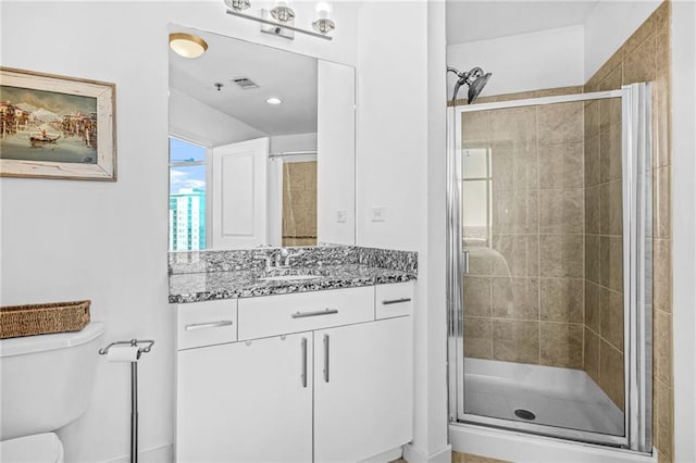 bathroom with vanity, toilet, visible vents, and a stall shower