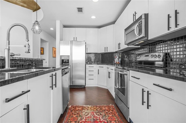 kitchen featuring visible vents, a sink, backsplash, appliances with stainless steel finishes, and white cabinets